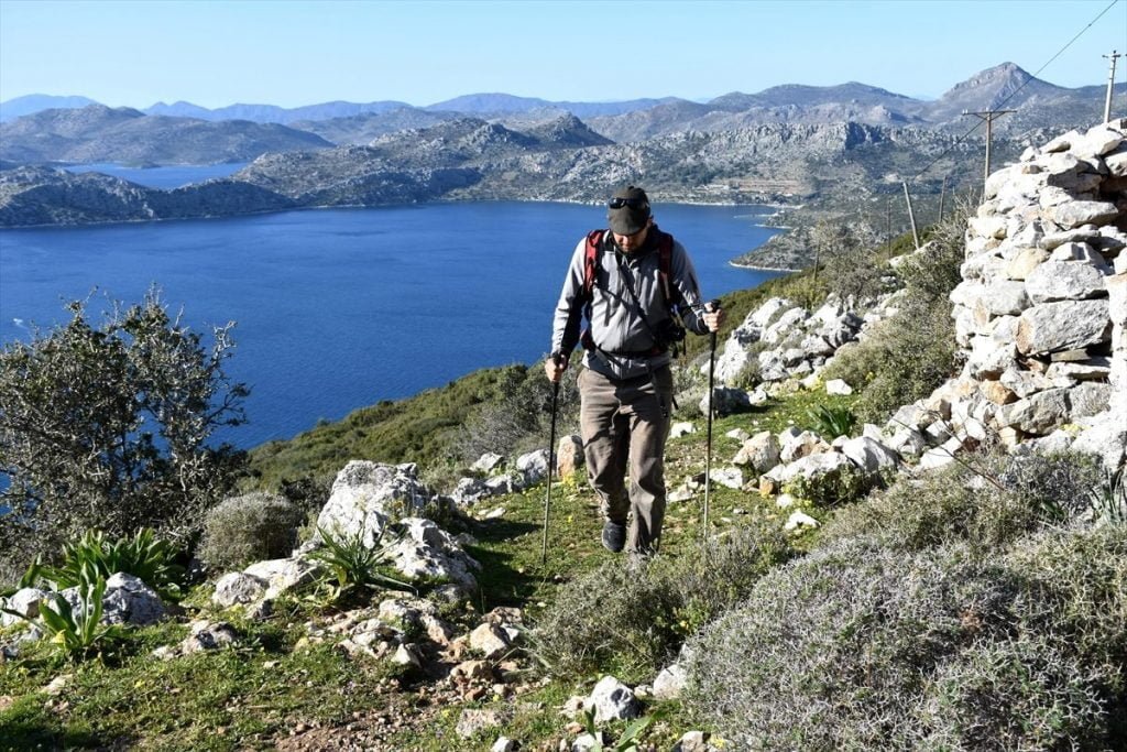 Karia Yolu kayalık sahil parkurunda batonlarla yürüyen erkek