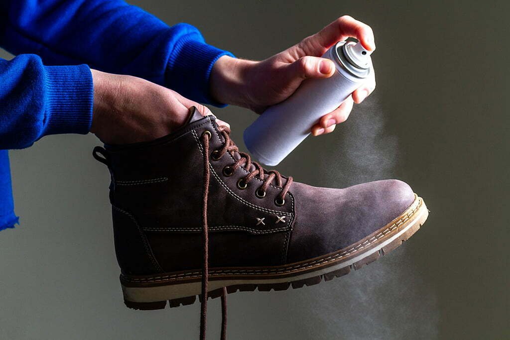 Outdoor bota su geçirmezlik spreyi uygulayan kişi