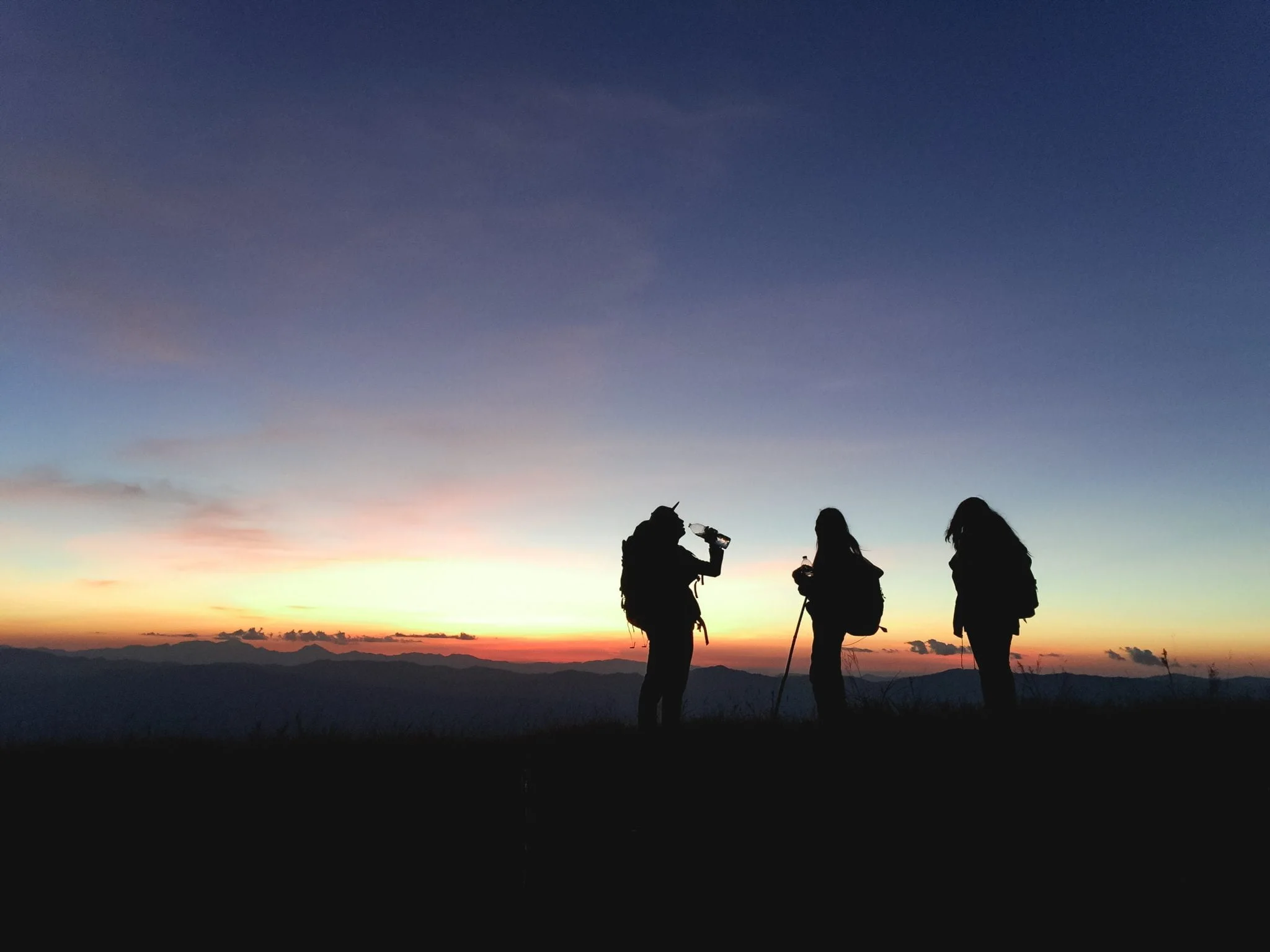 Gün batımında mola veren sırt çantalı trekking grubu