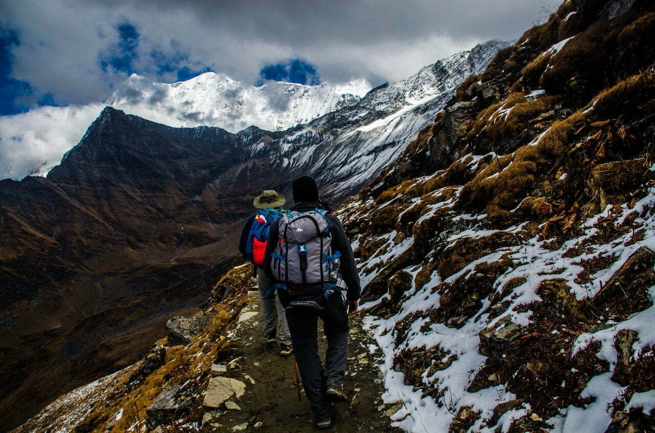Karlı dağ parkurunda sırt çantalarıyla trekking yapan iki yürüyüşçü