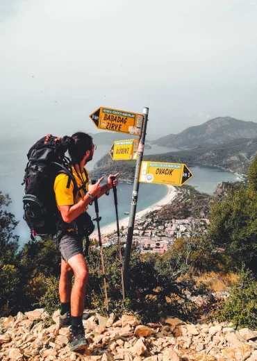 Likya Yolu uzmanı ve trekking tutkunu olarak, Fethiye Ölüdeniz'deki Babadağ ve Ovacık yön tabelalarının önünde doğa yürüyüşü yaparken.